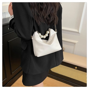 Detailed shot of white leather bag with elegant pearl handle and metal chain shoulder strap