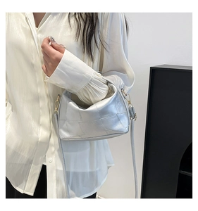 Detail of silver metallic crossbody bag with woven texture and gold metal buckle
