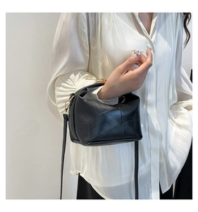 Detail of minimalist black bucket bag with geometric stitching and gold buckle
