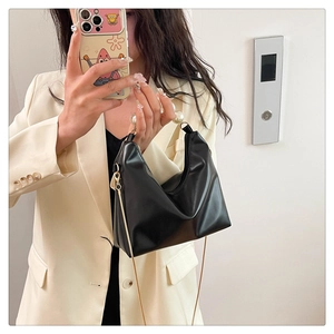Mirror selfie showing black glossy pearl handle bag with gold chain and crescent shape
