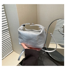 Detail of silver quilted handbag with matte texture and gold-tone metal hardware clasp