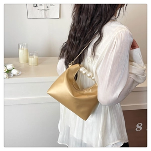 Detail of champagne gold hobo bag featuring large pearl handle and satin finish
