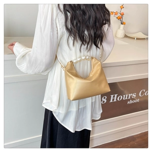 Detail showing elegant pearl handle and golden chain on a champagne mini handbag