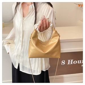 Detail of champagne gold hobo bag featuring large pearl handle and fine metal chain strap