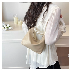 Detail view of beige crescent bag with large pearl handle and soft leather texture
