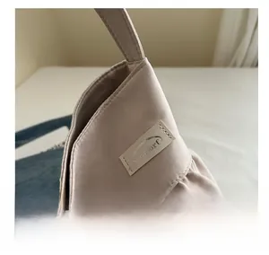 Close-up of beige satin ruffled tote bag featuring detailed stitching and premium branding tag