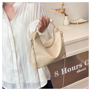 Close-up of elegant pearl handle and smooth matte beige PU leather on a mini handbag
