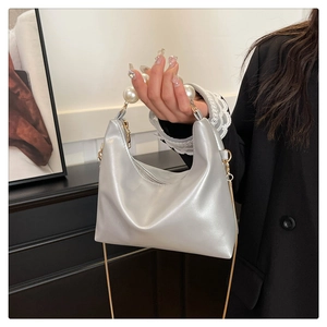 Close-up of a silver pearl handle handbag with a gold chain and shiny finish