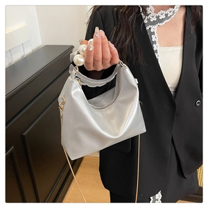 Detail of silver metallic handbag with pearl bead handle and gold chain strap
