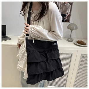 Detail of black ruffled canvas tote bag with adjustable strap in a lifestyle setting