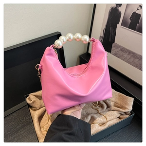 Detail of pink dumpling bag with pearl handle and golden chain inside a luxury gift box