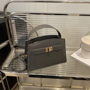 Sac à main Kelly en cuir grainé gris foncé avec fermoir doré sur étagère moderne