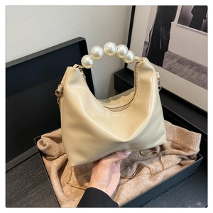Detail of elegant beige dumpling bag with large pearl handle and soft PU leather texture