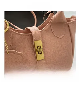 Detail der rosa Lederhandtasche mit goldenem Drehverschluss und Bärenanhänger