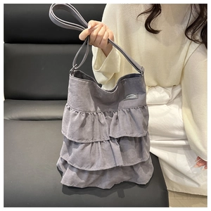 Detail view of the gray layered ruffle fabric tote bag with elegant texture and tag