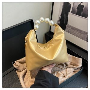 Detailed close-up of champagne pearl handbag handle and smooth faux leather texture