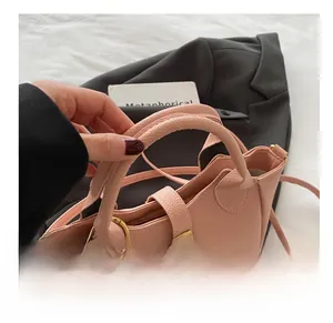 Detailansicht der rosa Tasche mit Litschi-Muster und eleganten goldenen Metallschnallen