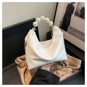Close-up of white mini dumpling bag with large pearl handle and gold chain detail