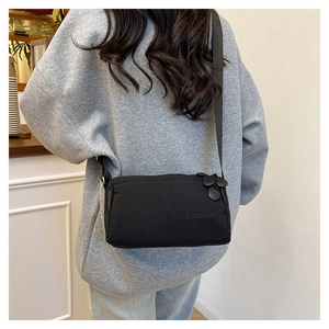 Détail macro du sac bandoulière en nylon noir avec logo de marque DUONING embossé