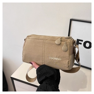 Détail du sac bandoulière kaki avec plusieurs poches zippées et une large sangle réglable