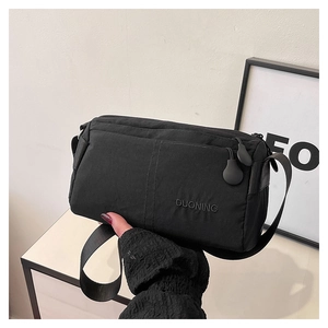 Detail of black textured crossbody bag with embossed logo and adjustable strap