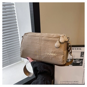 Detail view of khaki nylon shoulder bag featuring DUONING logo and three zipper pockets