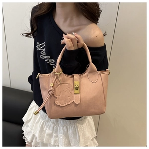 Détail du sac seau rose grainé avec fermoir doré et breloque en forme de chien