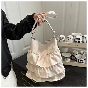 Detail of cream ruffled tote bag featuring three-layered pleats and brand logo tag
