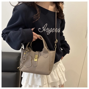 Détail du sac seau en cuir grainé avec fermoir rotatif doré et breloque en nuage