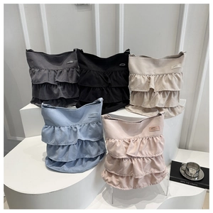 Detail of ruffled layered tote bags in gray, black, beige, blue and pink colors
