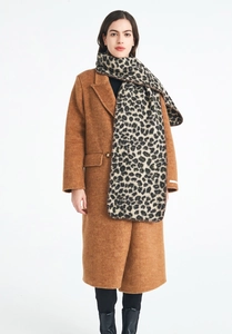Detailed view of heavy leopard print scarf paired with a classic camel wool coat