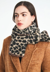 Detail of green leopard print scarf with brown stitched edges on caramel coat