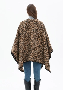 Close-up of thick knit leopard print shawl with black fabric trim and plush texture