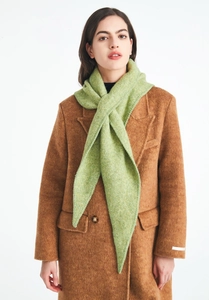 Detail of green tweed knit triangle scarf styled on a tan wool coat against a white background
