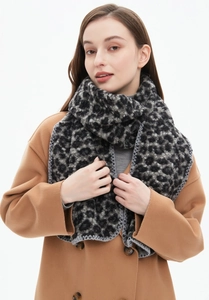 Macro detail of thick leopard print scarf featuring grey overlock stitched edges and soft texture