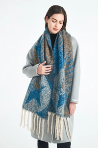 Close-up of thick winter scarf featuring blue and brown star jacquard and long cream tassels