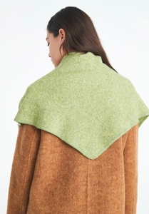 Detail of green knitted triangle shawl draped over a camel wool coat on a model
