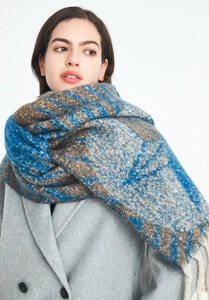 Detail of chunky knit scarf featuring blue and brown star patterns with thick beige tassels