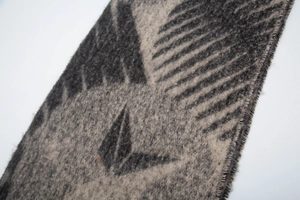 Close-up of thick knitted star pattern scarf with grey boucle yarn and fringe details