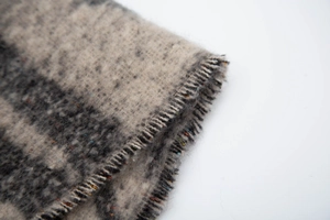 Close-up of fringe tassels and soft brushed jacquard star pattern on winter scarf