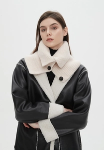 Close-up of cream knit snarf collar with vertical ribs and dark brown buttons on a model