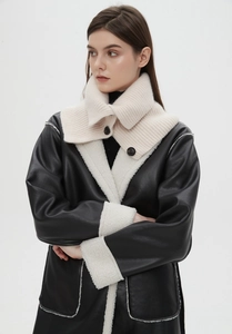 Detail of knit collar with buttons on a black faux leather coat with white shearling trim