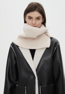 Detail of cream chunky knit wool scarf paired with black leather faux shearling coat
