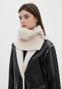Detail of cream white ribbed knit neck warmer paired with a black faux shearling biker jacket