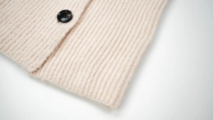 Detail of winter wool knit scarf showing ribbed texture and a marble resin button