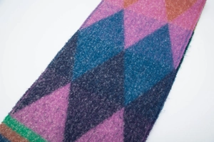 Detail of colorful argyle knit scarf featuring soft bouclé texture and frayed fringe edges