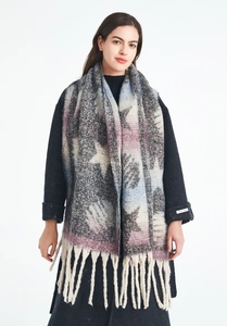 Close-up of star pattern knit scarf with fringe tassels and hand made label detail