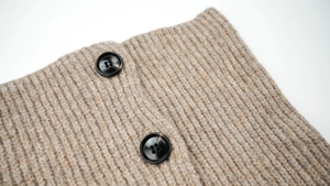 Macro shot of oatmeal rib-knit wool fabric with two amber-textured resin buttons