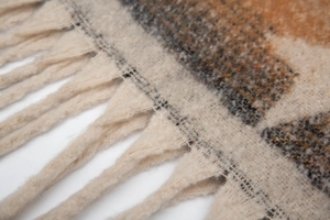 Close-up of tricolor star pattern knit scarf featuring thick handmade braided tassels