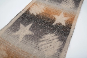 Close-up of knit star pattern and soft fringe detail on thick winter scarf shawl